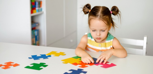 Niña haciendo un puzle con piezas de colores